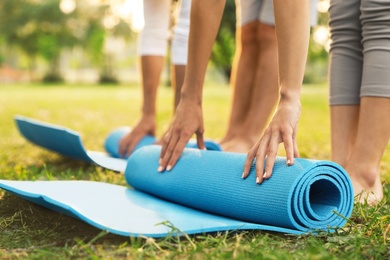 People rolling up yoga mat in park at morning, closeup