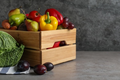 Wooden crate full of different vegetables and fruits on grey table, space for text. Harvesting time