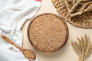 Wheat grains and spikes on white wooden table, flat lay