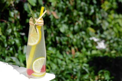 Refreshing tasty lemonade served in glass bottle on white wooden surface. Space for text