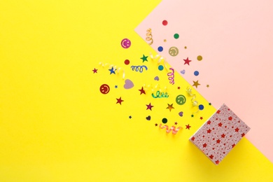 Shiny confetti and box on color background, top view. Space for text