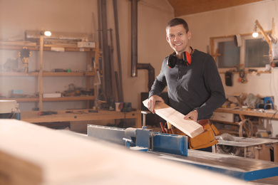 Professional carpenter working with surface planer in workshop