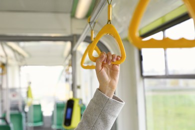 Woman holding handgrip handle in public transport, closeup