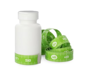 Jar of weight loss pills and measuring tape on white background