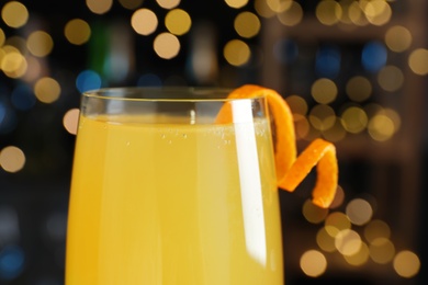 Mimosa cocktail with garnish against blurred lights, closeup