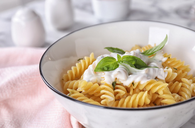 Delicious pasta with sauce and basil on table, closeup view
