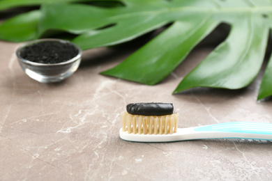 Toothbrush with natural bristles and charcoal paste on grey marble table, closeup. Space for text