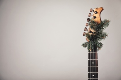Guitar with fir tree branch on light background, space for text. Christmas music