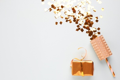 Flat lay composition with golden confetti and box on light background, space for text