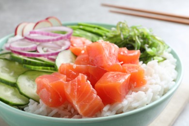 Delicious poke bowl with salmon, rice and vegetables on table, closeup