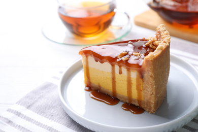 Slice of delicious cake with caramel sauce on table
