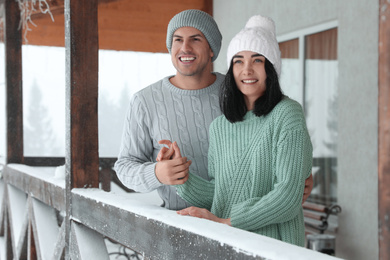 Lovely couple wearing warm sweaters and hats outdoors on snowy day. Winter season