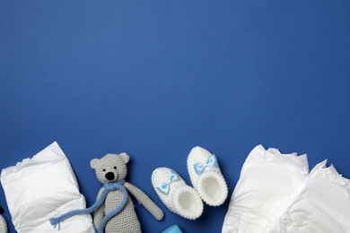 Photo of Diapers and baby accessories on blue background, flat lay. Space for text
