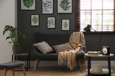 Beautiful artworks and comfortable sofa in stylish room. Interior design