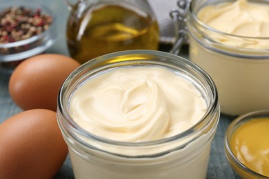 Photo of Delicious homemade mayonnaise with ingredients on light blue wooden table, closeup