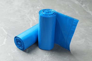 Rolls of light blue garbage bags on grey marble table