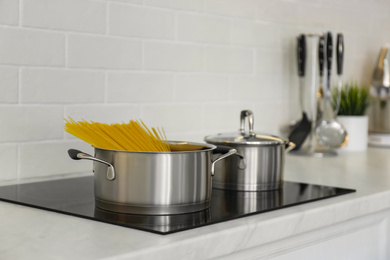 Saucepan with uncooked pasta on stove in kitchen