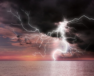 Dark cloudy sky with lightning striking sea. Picturesque thunderstorm 