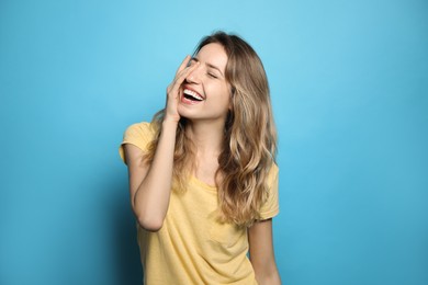 Photo of Cheerful young woman laughing on light blue background