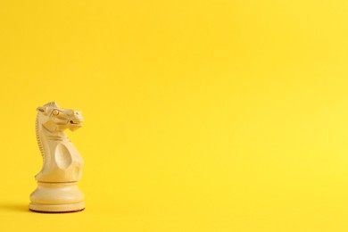 Wooden knight on yellow background, space for text. Chess piece