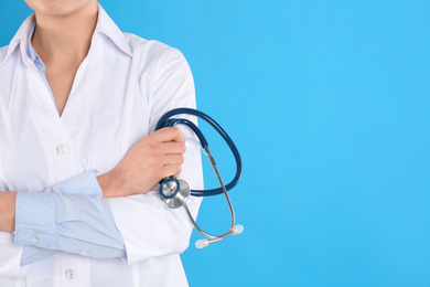 Photo of Closeup view of young doctor with stethoscope on blue background, space for text