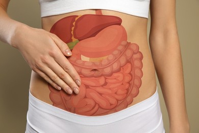 Image of Closeup view of woman with illustration of abdominal organs on her belly against beige background