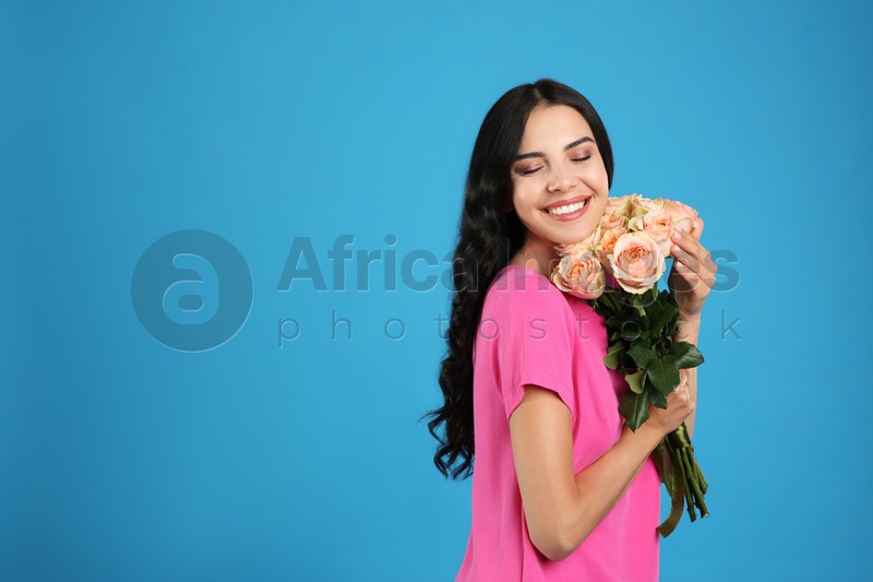 Portrait of smiling woman with beautiful bouquet on light blue background. Space for text