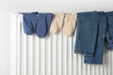 Jeans and socks on heating radiator near white wall