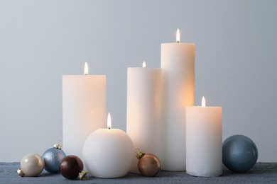 Burning candles and Christmas baubles on grey wooden table