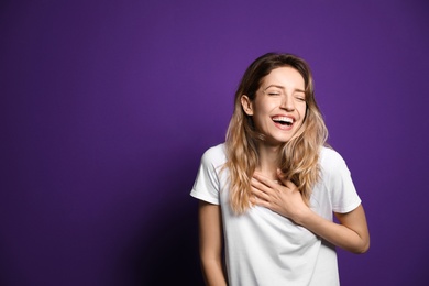 Photo of Cheerful young woman laughing on violet background. Space for text