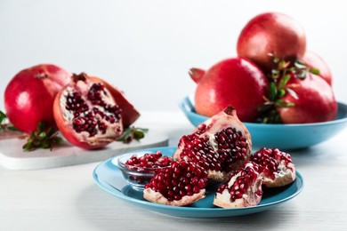 Delicious ripe pomegranates on white wooden table