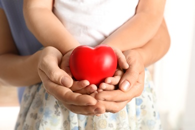 Adult and child hands holding heart on light background, closeup. Family concept