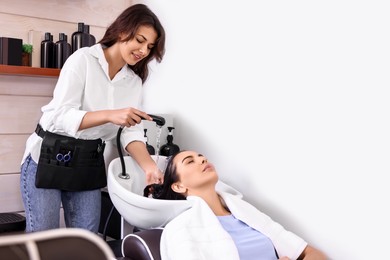 Photo of Professional hairdresser washing woman's hair in beauty salon