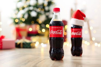 MYKOLAIV, UKRAINE - January 01, 2021: Bottles of Coca-Cola on floor against blurred Christmas lights