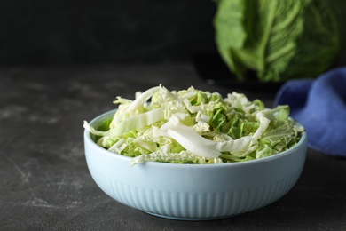 Photo of Cut fresh savoy cabbage in bowl on grey table, closeup