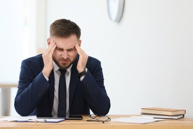 Man suffering from migraine at workplace in office. Space for text