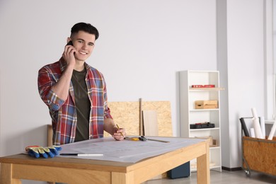 Photo of Young handyman talking on phone in room