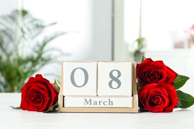 Wooden block calendar with date 8th of March and roses on table indoors, space for text. International Women's Day