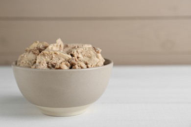 Photo of Bowl of tasty cod liver on white wooden table. Space for text