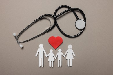 Paper family figures, red heart and stethoscope on light grey background, flat lay. Insurance concept