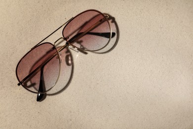 Stylish sunglasses on sand, top view. Space for text