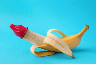 Banana with condom on light blue background. Safe sex concept