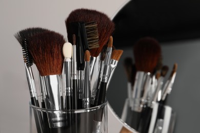 Photo of Set of professional brushes and mirror on grey background, closeup