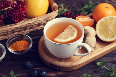Photo of Cup of delicious immunity boosting tea and ingredients on wooden table