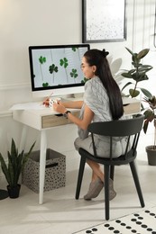 Photo of Young woman working at table in light room. Home office