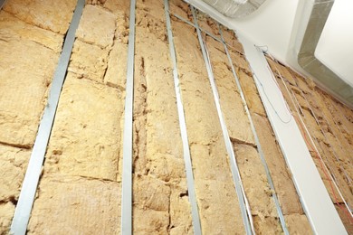 Photo of Wall with metal studs and insulation material indoors, low angle view