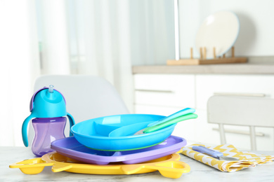 Photo of Set of plastic dishware on white marble table indoors. Serving baby food