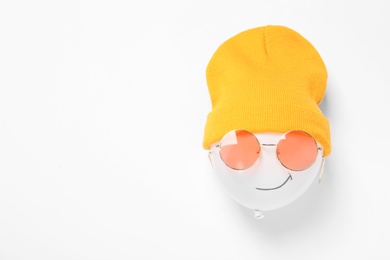 Photo of Funny face made of balloon, hat and sunglasses on white background, top view. Space for text