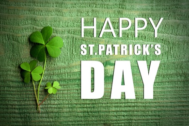 Image of Happy St. Patrick's Day. Clover leaves on green wooden table, flat lay