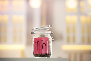 Tip jar with money on table against blurred background
